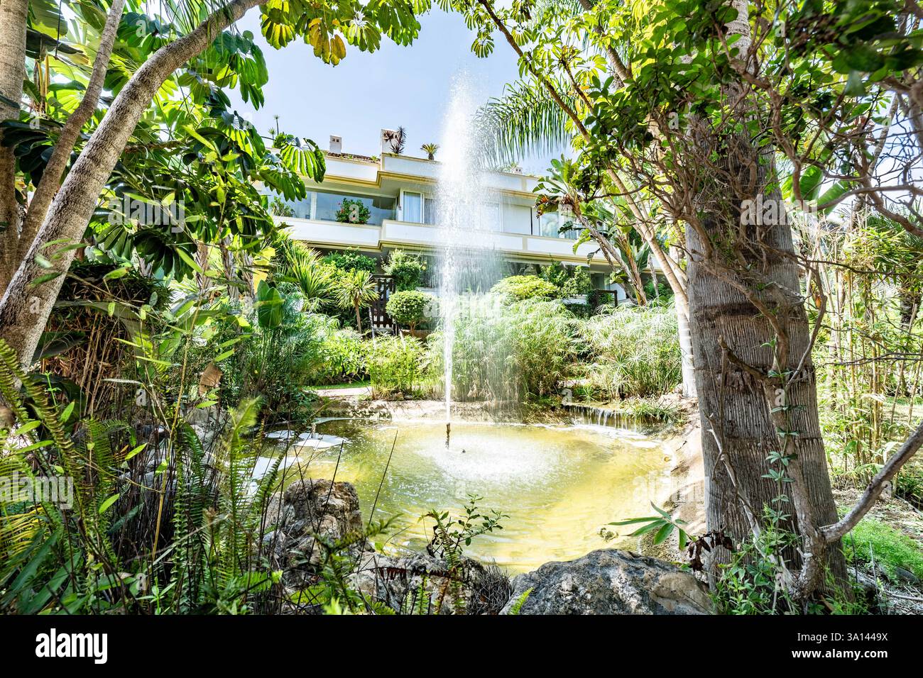 Ein Bild eines Gemeinschaftsgartens mit Teichen und Springbrunnen in der mediterranen Ferienanlage Stockfoto
