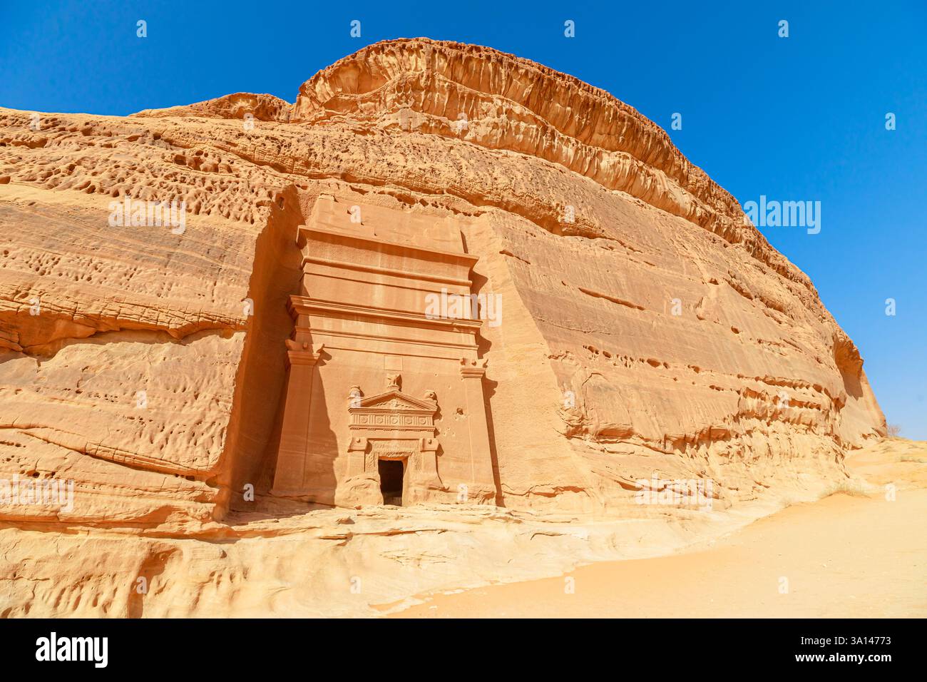 Sonnenlicht beleuchtet die komplizierte Fassade eines Nabatäischen Grabes, das in Sandsteinklippen von Jabal AlBanat in der antiken Stadt Hegra, die UNESCO gehört, gehauen wurde Stockfoto