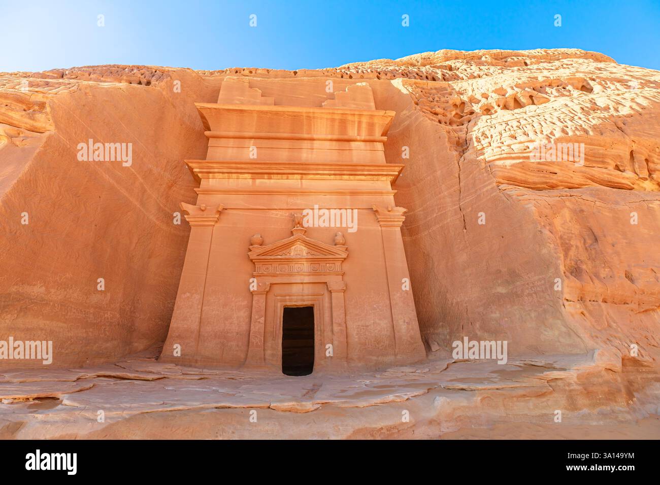 Das Sonnenlicht beleuchtet die aufwändig geschnitzte Fassade eines Nabatäischen Grabes von Jabal AlBanat in Hegra und zeigt die reiche Geschichte und Architektur Stockfoto