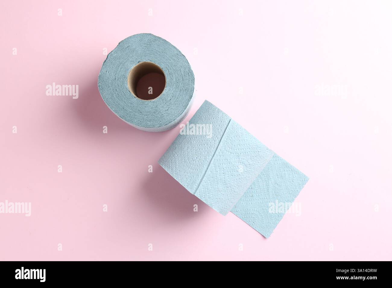 Blaue Toilettenpapierrollen auf hellrosa Hintergrund, Draufsicht Stockfoto