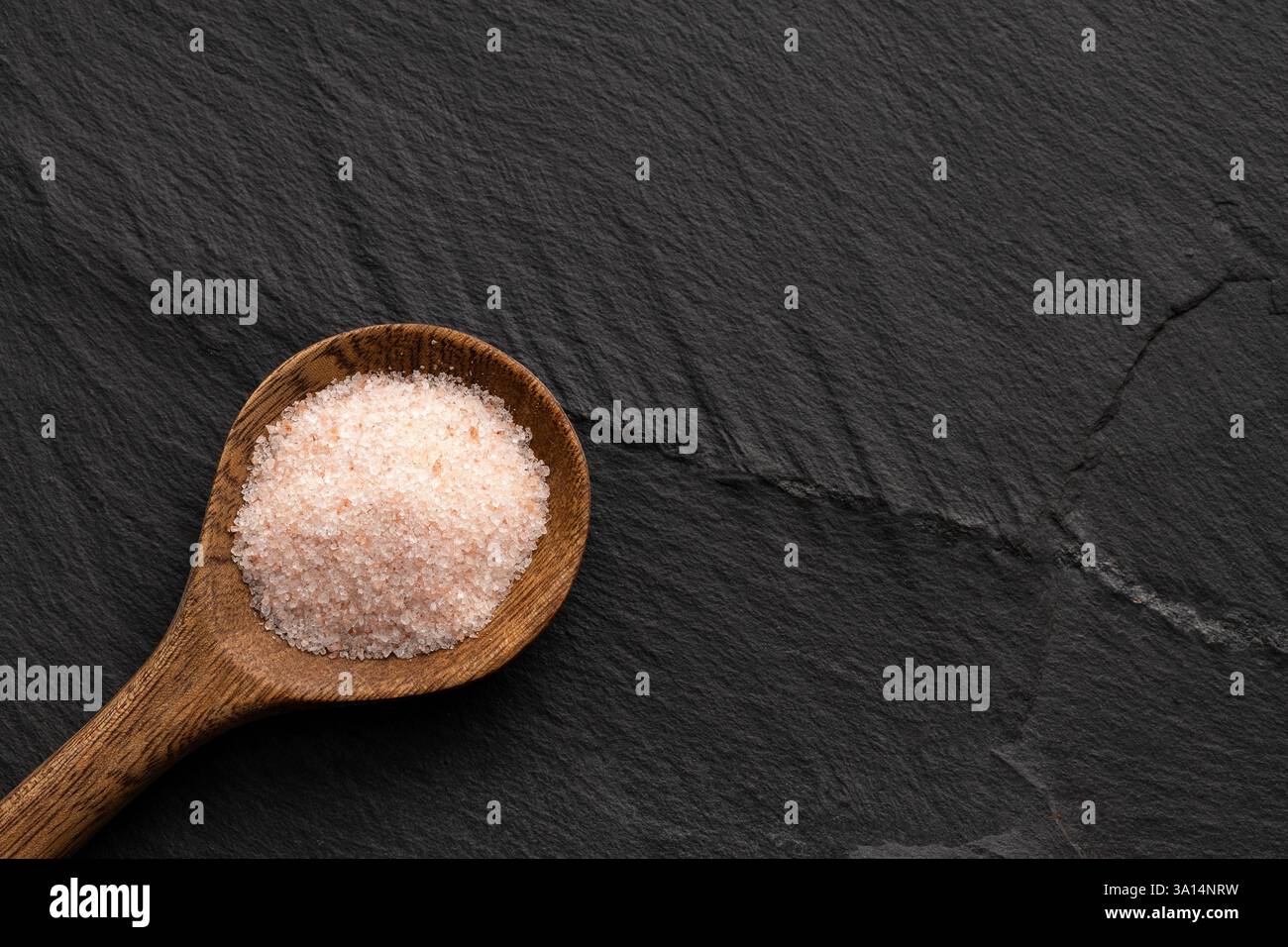 Feines Salz und rosafarbene Himalaya-Kristalle auf dem Löffel. Stockfoto