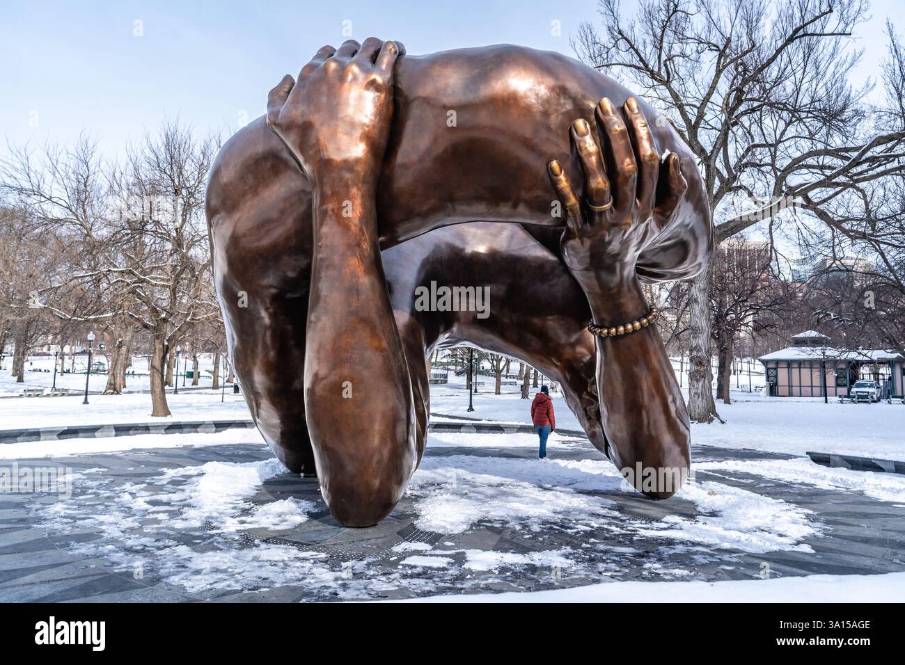 Boston, MA, USA – 11. Februar 2025 – Eine Frau, die in der Nähe der Embrace steht, einer Bronzeskulptur von Hank Willis Thomas, die auf Bos installiert wurde Stockfoto