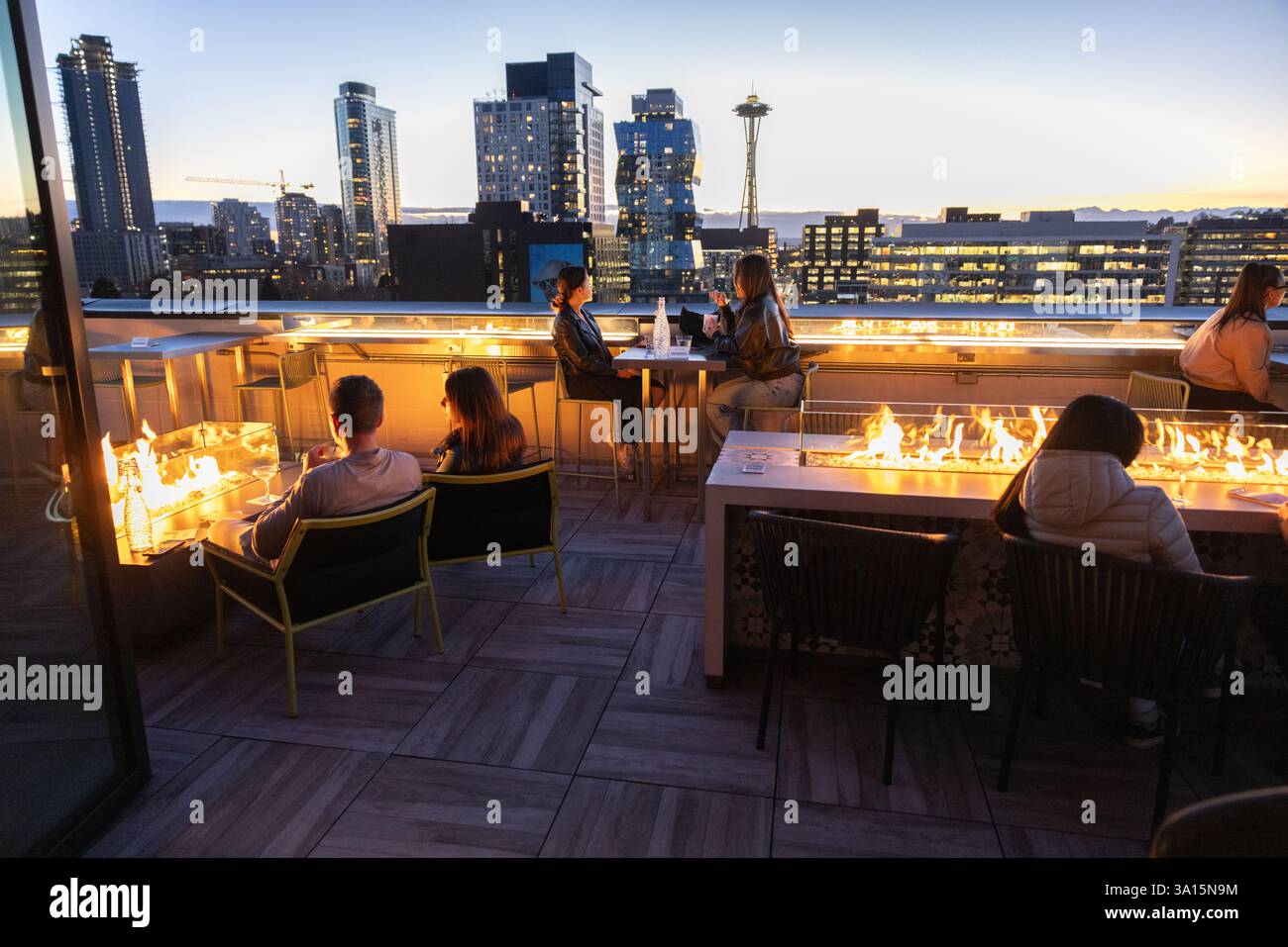Die Leute trinken Cocktails mit Blick auf die Skyline von Seattle und Space Needle mit dem Puget Sound und den Olympic Mountains in der Ferne. Stockfoto