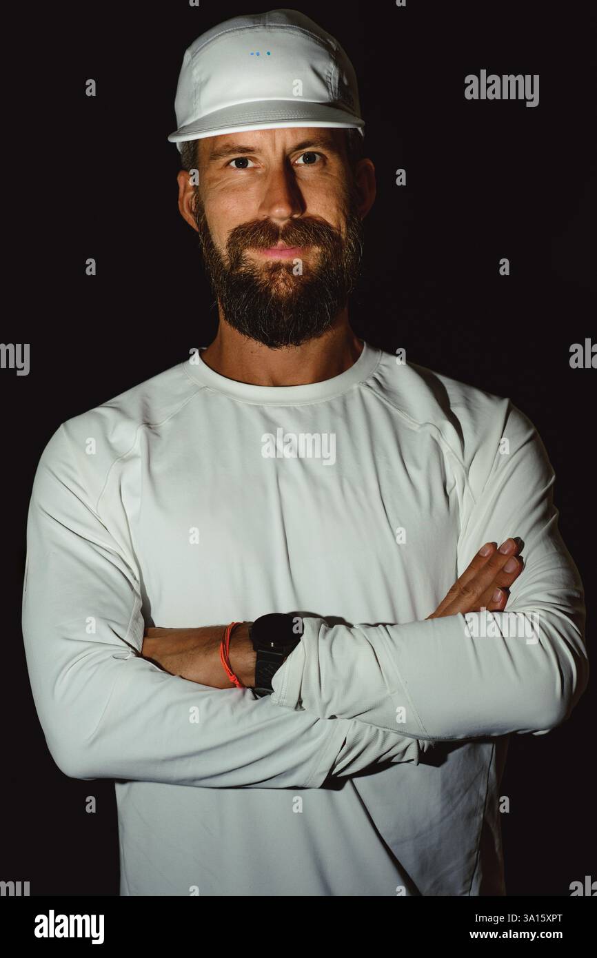Porträt eines jungen bärtigen Mannes mit Hemd und Hut auf schwarzem Hintergrund Stockfoto
