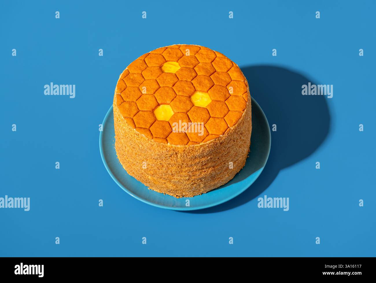 Honigkuchen namens Medovik, in hellem Licht isoliert auf blauem Hintergrund Stockfoto