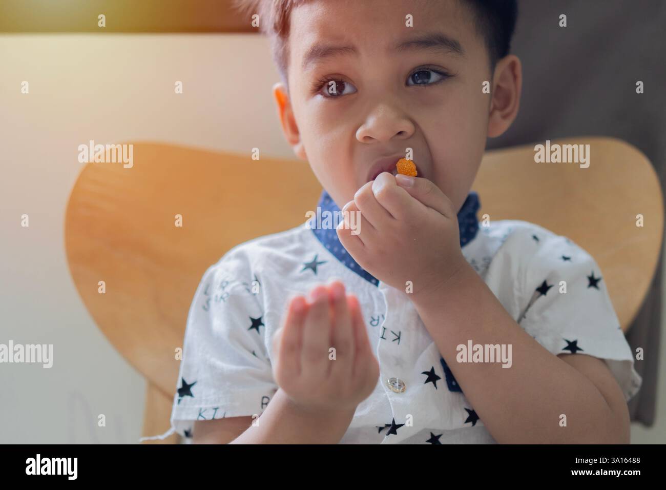 Portraitbild eines kleinen asiatischen Kindes, Junge 3 Jahre alt will gallertartige Süßigkeiten essen. Selektiver Fokus. Stockfoto