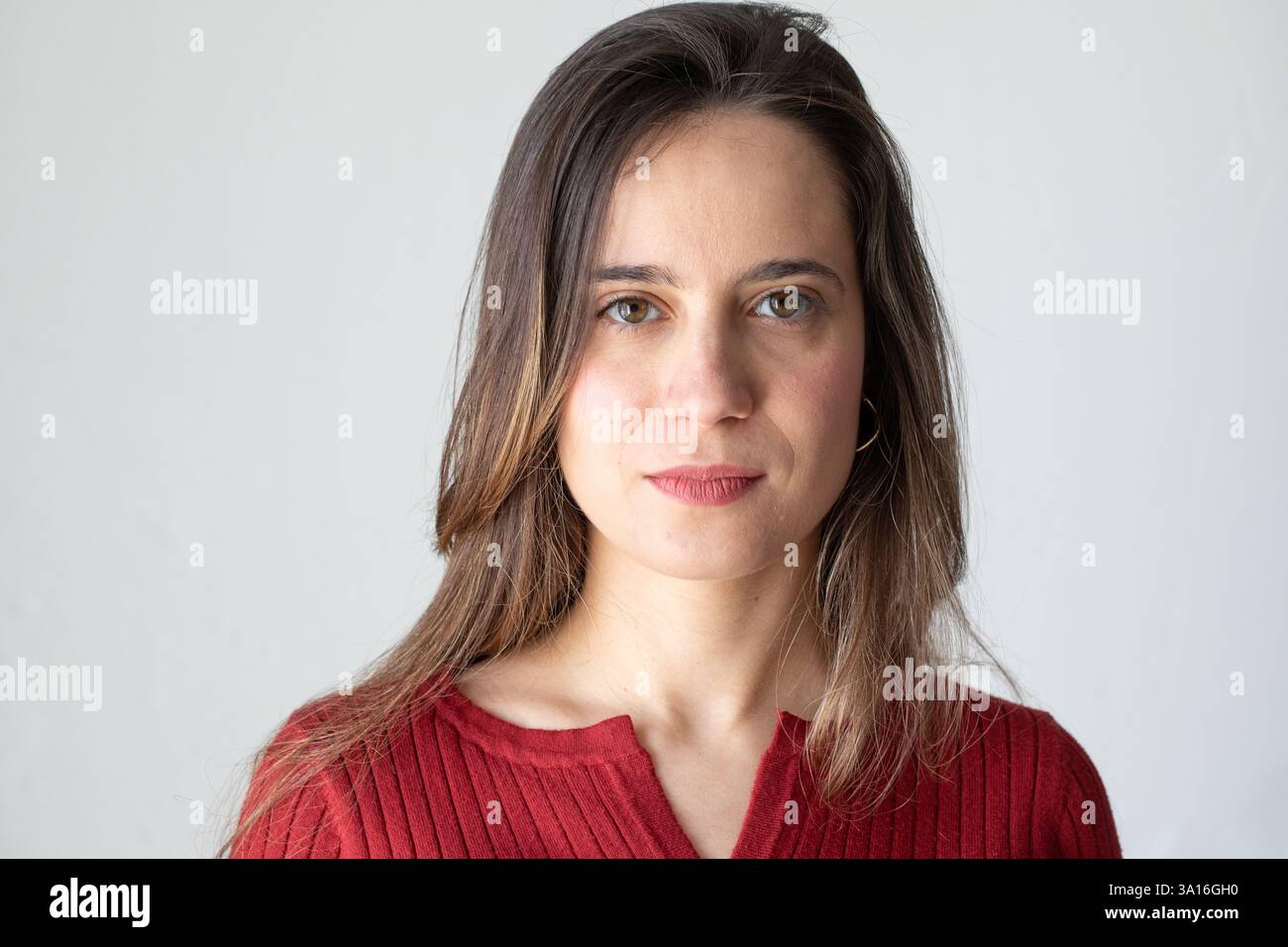 Studio-Porträt einer selbstbewussten jungen Frau in roter Bluse, posiert vor weißem Hintergrund Stockfoto