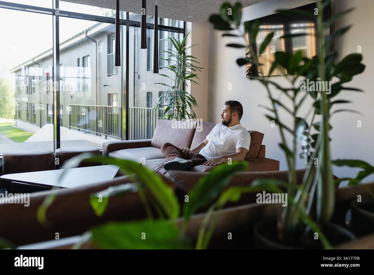Hübscher junger Erwachsener, der auf der Couch am Fenster liegt Stockfoto