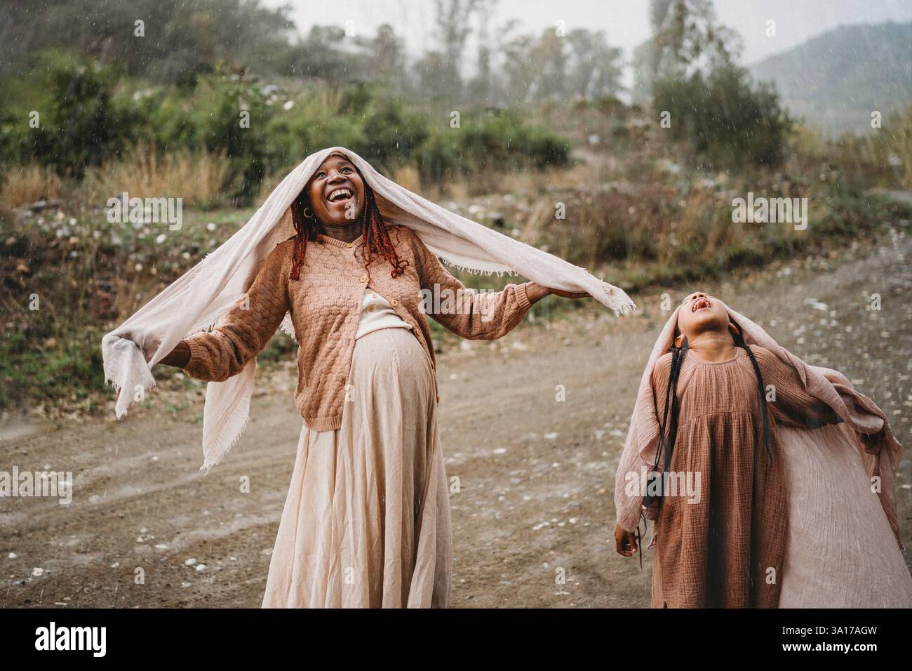 Glückliches schwarzes Mädchen, der Regen fühlt Freude, schwangere Mutter die Zunge rauszustechen Stockfoto
