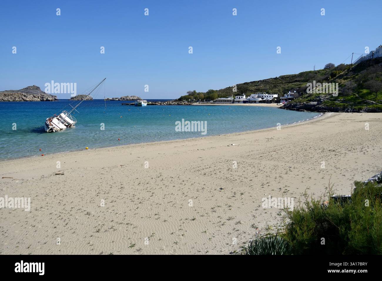 Lindos Strand mit einer teilweise untergetauchten Yacht im klaren blauen Wasser. Stockfoto