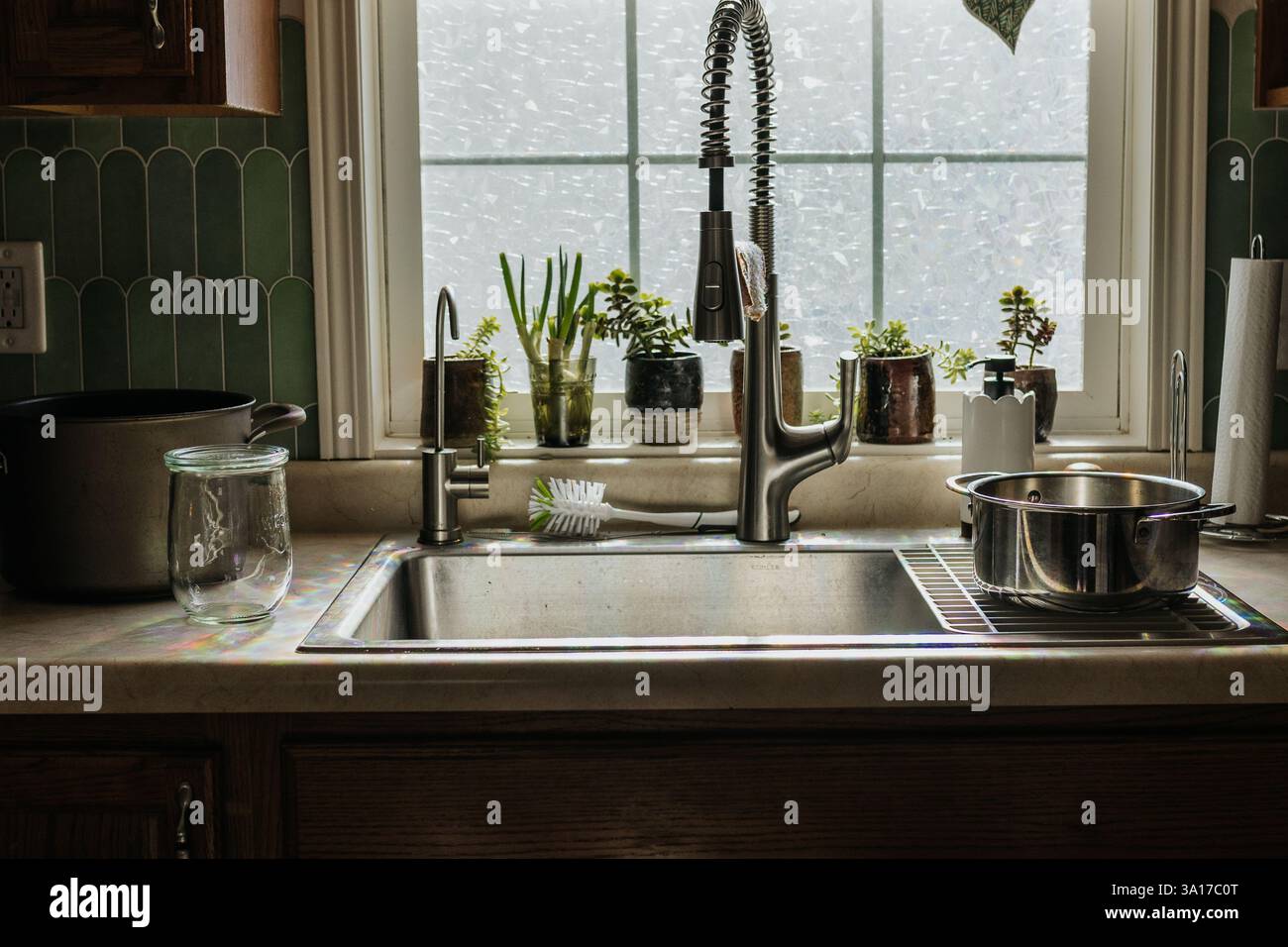 Blick auf das Küchenbecken vor dem Fenster mit Töpfen und Pflanzen Stockfoto