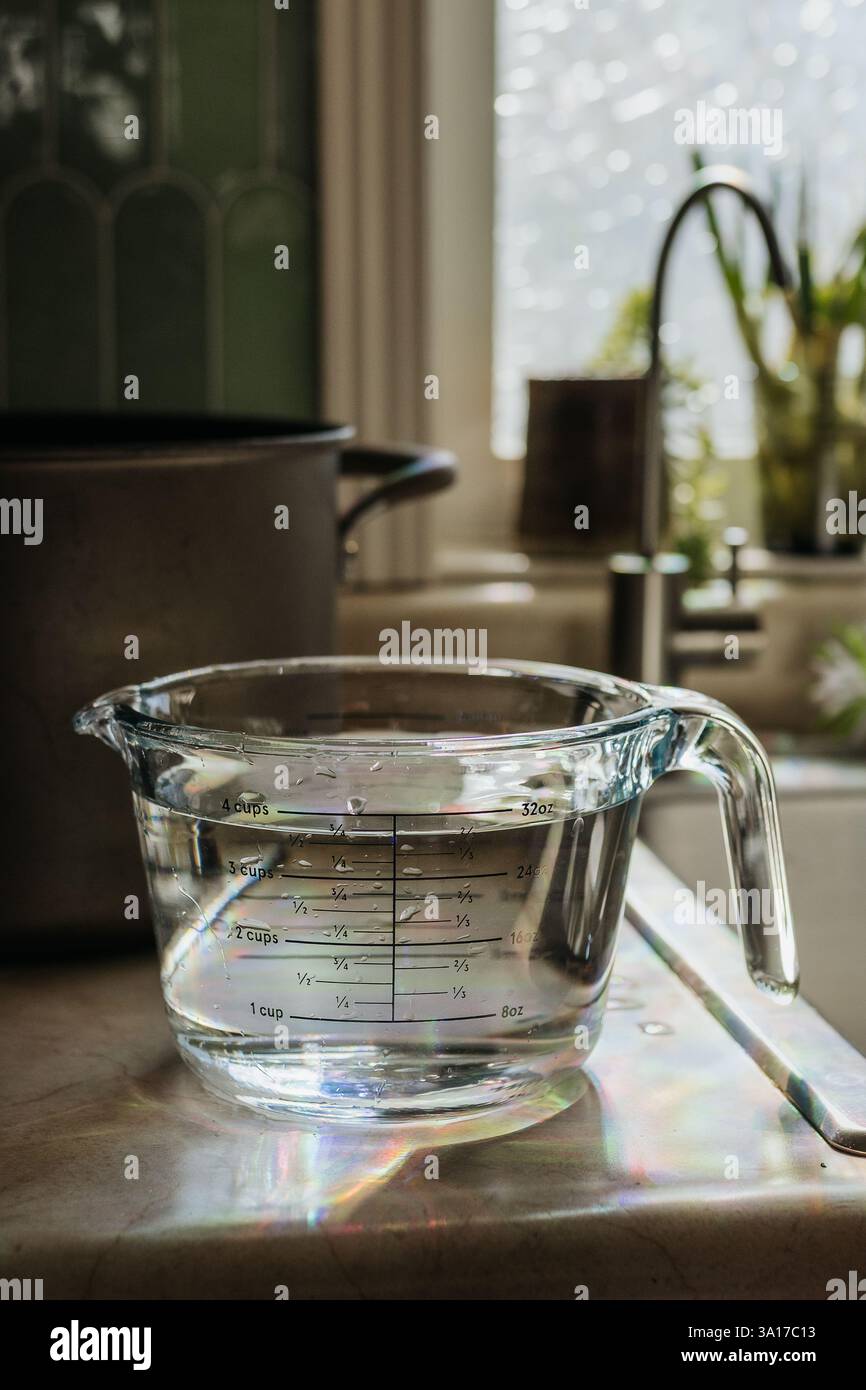 Der flüssige Messbecher steht auf der Küchenzeile mit Wasser Stockfoto