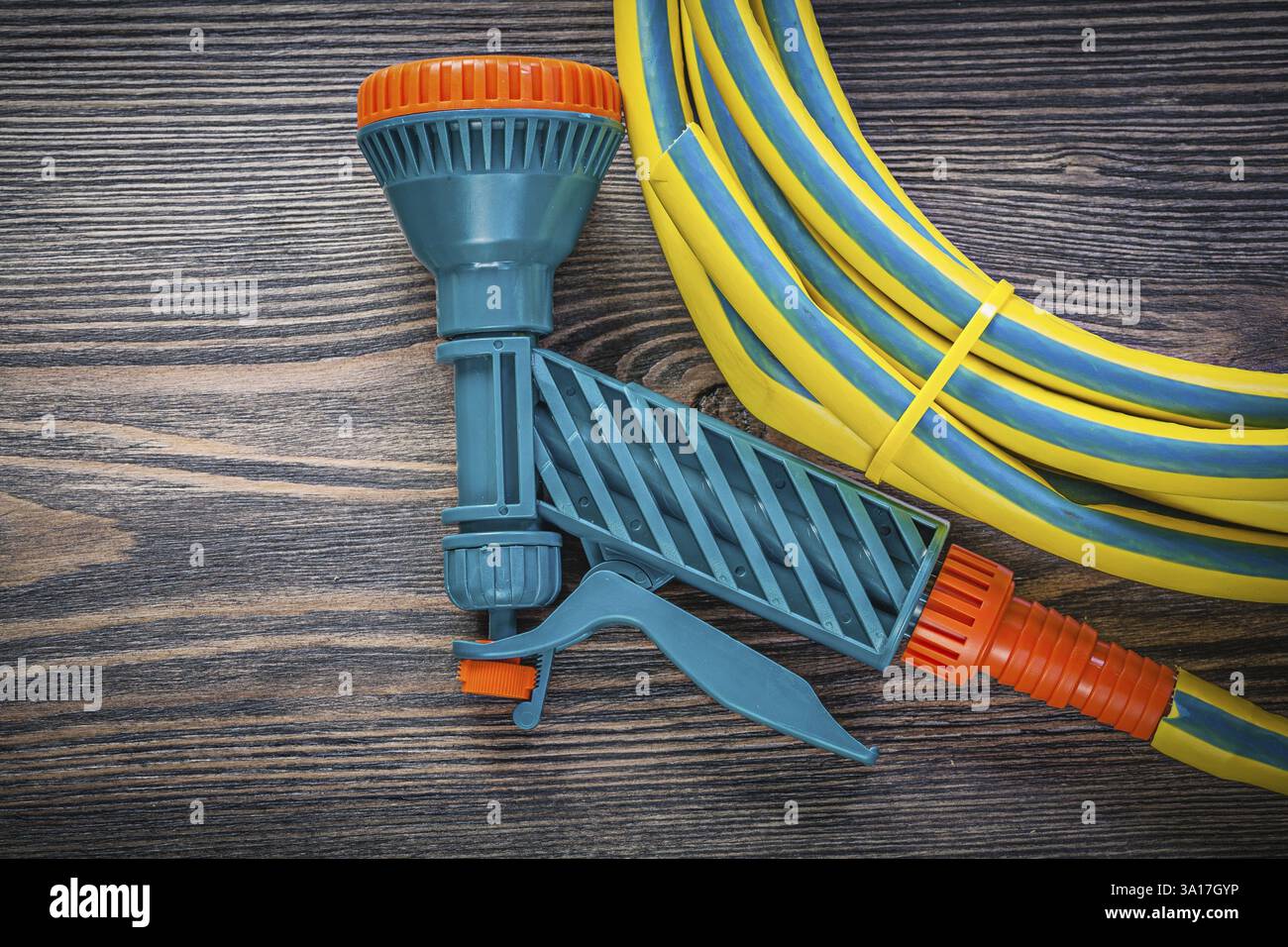 Spiralgummischlauch-Wassersprüher auf Holzbrett-Gartenkonzept Stockfoto
