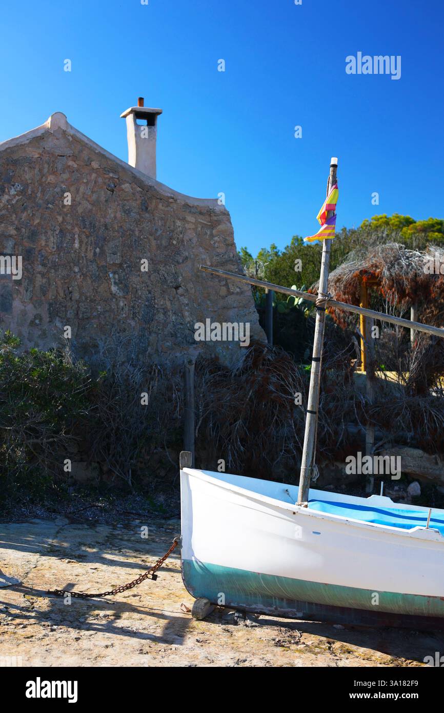 Altes verlassenes Boot in der Nähe eines Hauses am Meer. Altes verlassenes Boot mit Flagge in der Nähe des Hauses am Meer. Altes Tonsteinhaus. Weißes Boot mit Mast Stockfoto