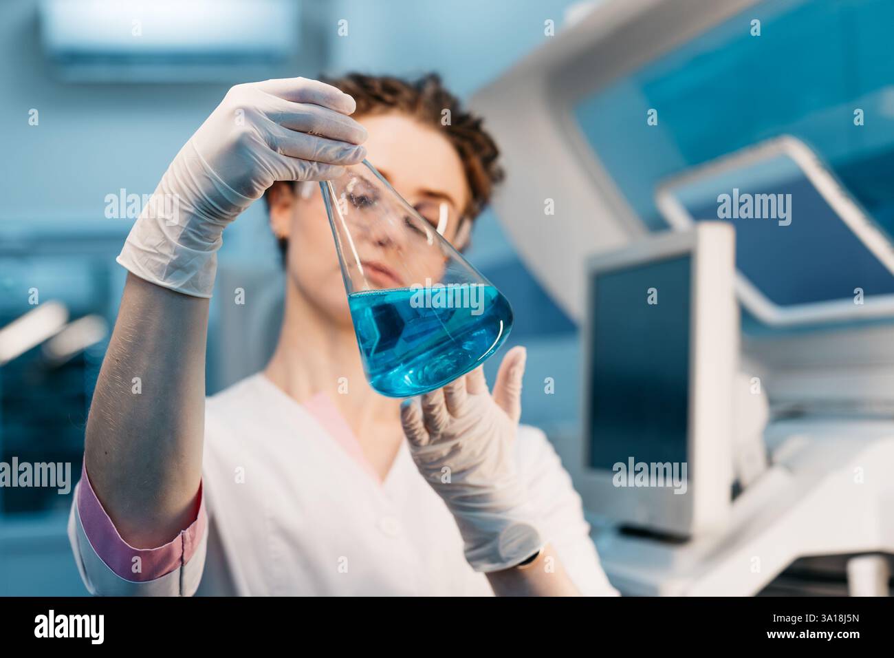 Ein Spezialist in einem Labor hält eine Flüssigkeit und analysiert sie. Das Konzept: Einsatz von High-Tech-Methoden für genaue Analysen und wissenschaftliche Forschung. Stockfoto