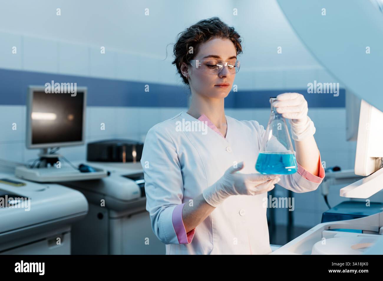 Ein Spezialist in einem Labor hält eine Flüssigkeit und analysiert sie. Das Konzept: Einsatz von High-Tech-Methoden für genaue Analysen und wissenschaftliche Forschung. Stockfoto