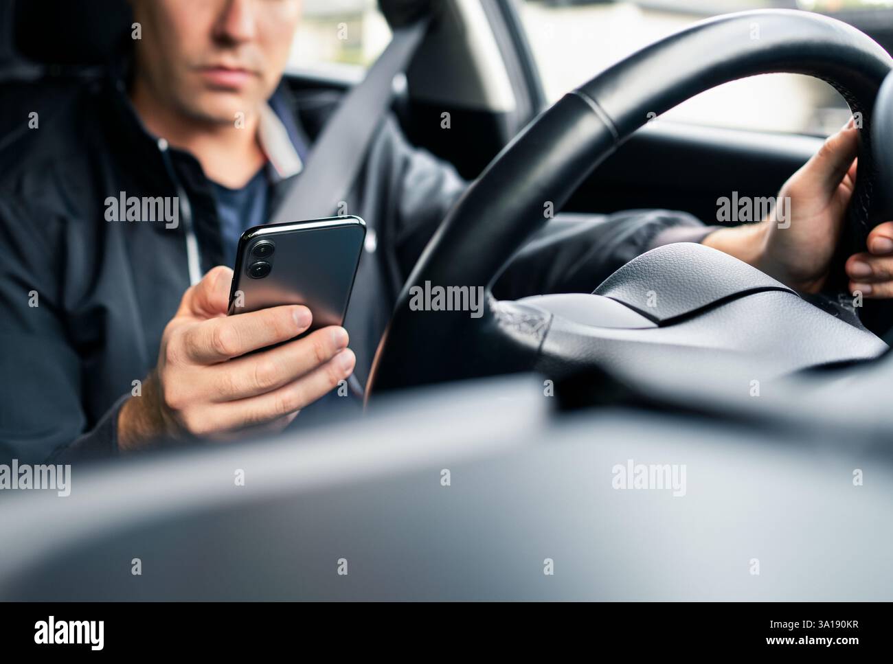 Das Fahren wird vom Telefon abgelenkt. Textnachrichten für Autofahrer. Unfall- und Unfallgefahr. Mann, der auf der Straße ein Handy benutzt. Unverantwortlicher Kerl, der sms benutzt. Stockfoto