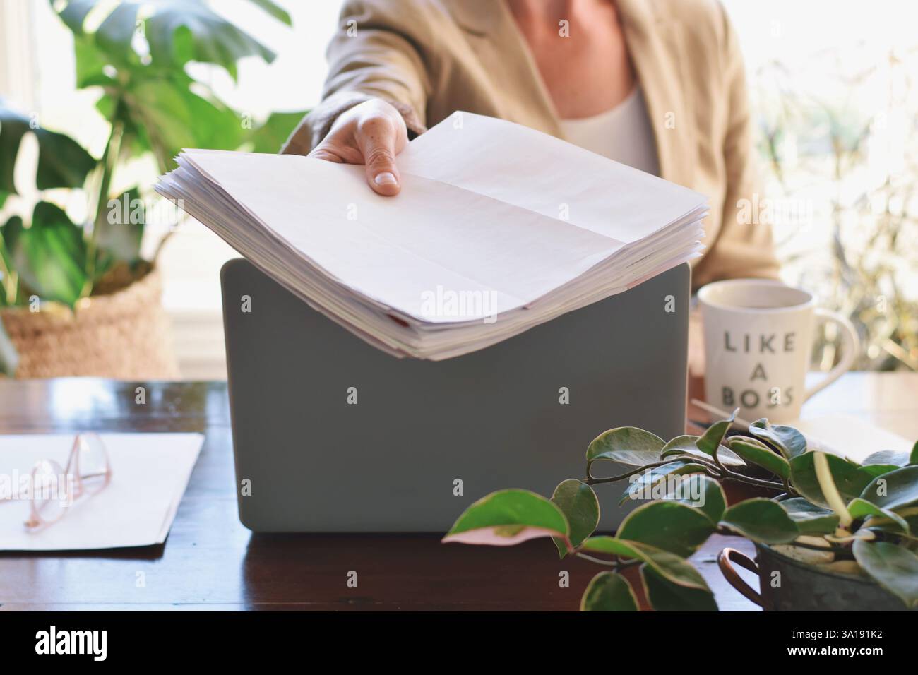 Die Frau sitzt an einem Schreibtisch und gibt jemandem Papiere Stockfoto
