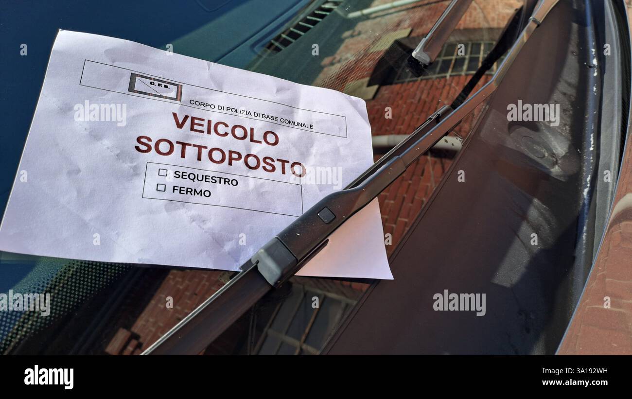 Behördliche Beschlagnahme eines Fahrzeugs, eines Fahrzeugs, das beschlagnahmt oder beschlagnahmt wird. Blatt Papier mit italienischer Schrift unter dem Frontscheibenwischer auf der linken Seite. Stockfoto Behördliche Beschlagnahme eines Fahrzeugs, eines Fahrzeugs, das beschlagnahmt oder beschlagnahmt wird. Blatt Papier mit italienischer Schrift unter dem Frontscheibenwischer auf der linken Seite. Stockfoto