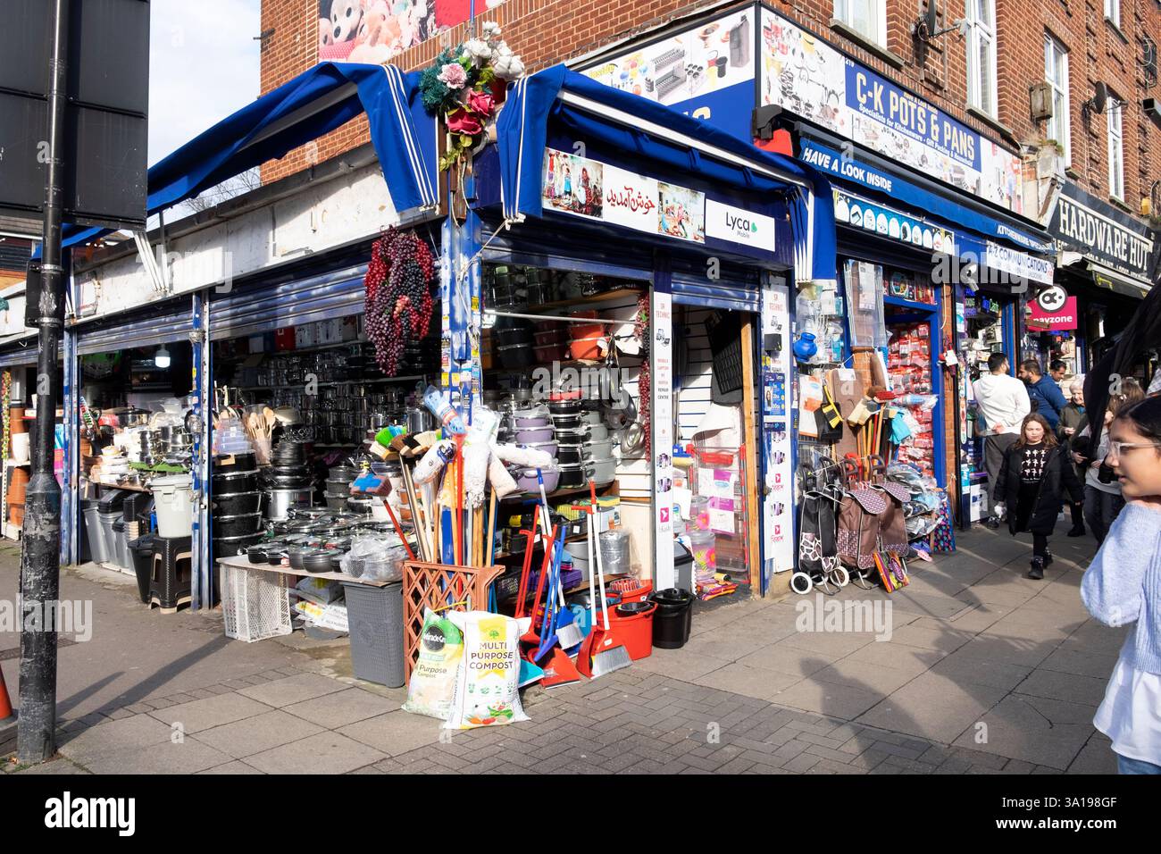 Menschen Fußgänger, die vor einem Eckgeschäft vorbeilaufen, das Haushaltsartikel verkauft, in der Walthamstow High Street London W17 England Großbritannien KATHY DEWITT Stockfoto