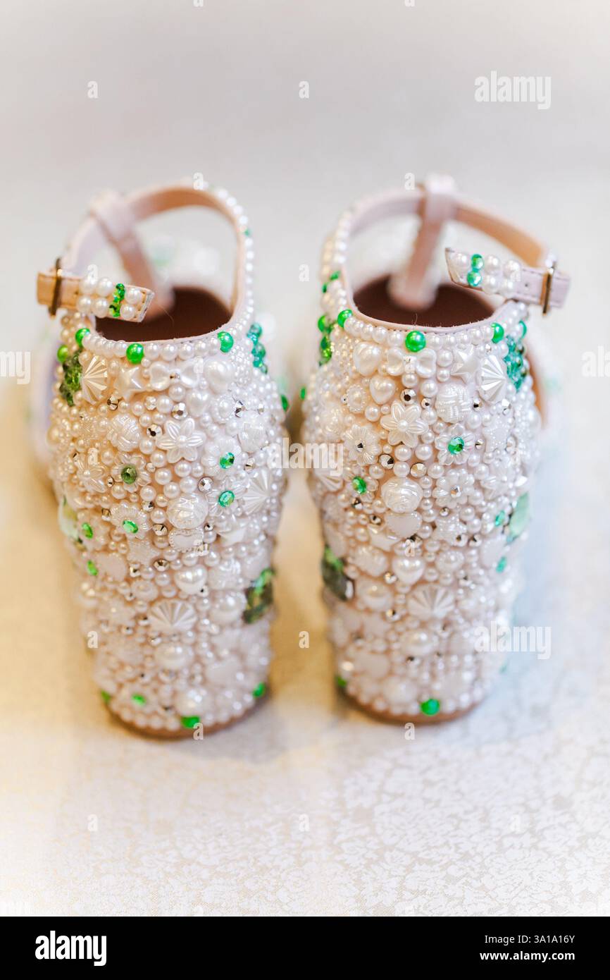 Wunderschöne Schuhe, die mit Perlen und grünen Edelsteinen verziert sind und exquisite Handwerkskunst für Feiern zeigen. Stockfoto