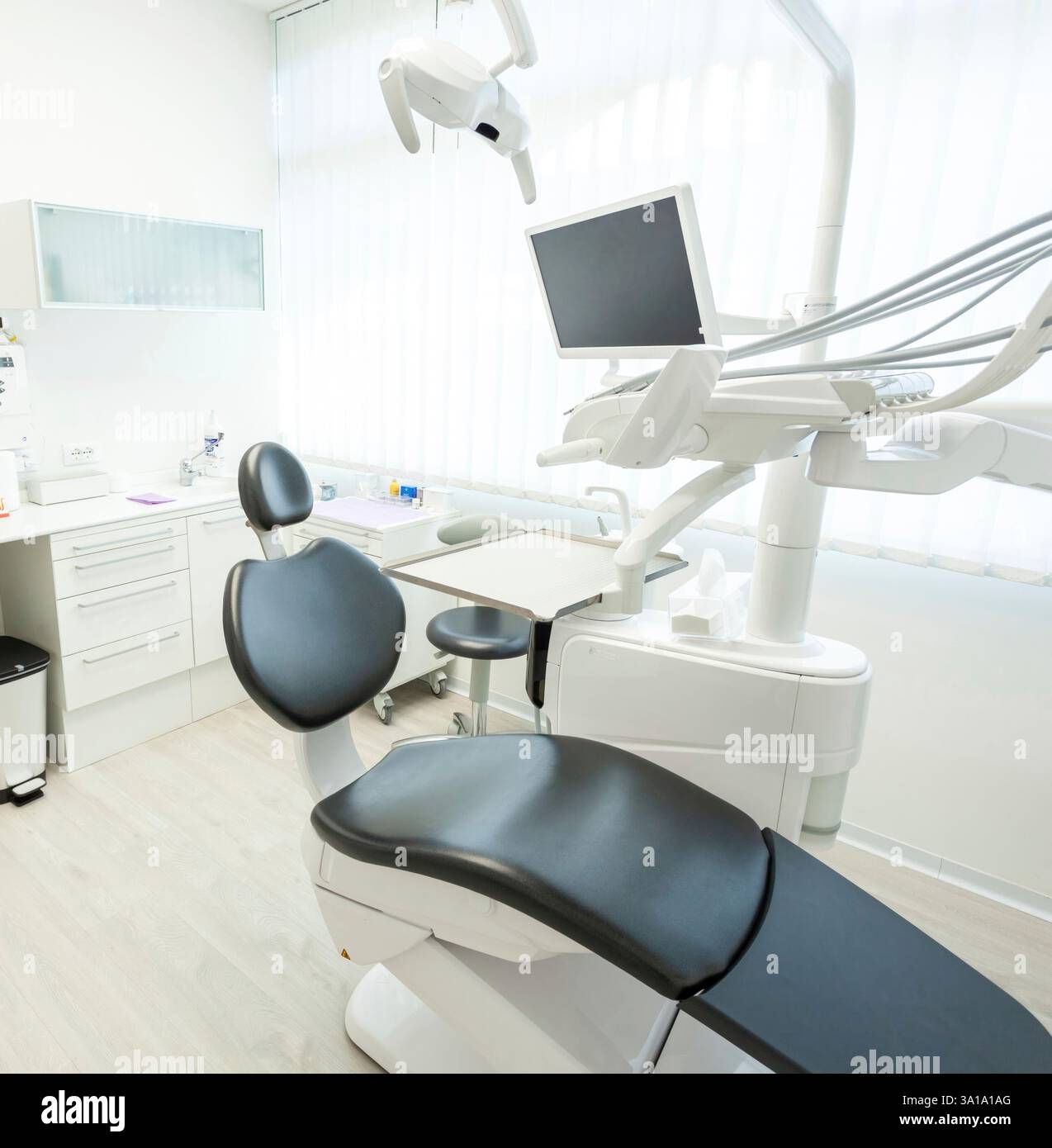 Helle und moderne Zahnarztpraxis mit professioneller Ausstattung, einem bequemen Stuhl und einem Monitor für eine saubere und einladende Atmosphäre Stockfoto