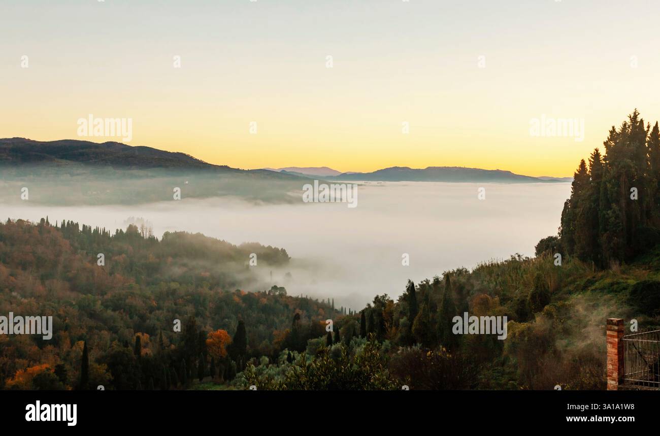 Nebel bedeckt das Tal in der toskanischen Landschaft bei Sonnenaufgang und bietet einen atemberaubenden Blick auf die Schönheit der Natur Stockfoto