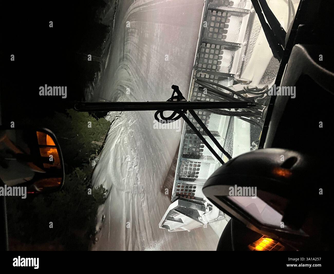 Schneepflug-Fahrer arbeiten fleißig daran, nachts eine schneebedeckte Bergstraße zu räumen und sich durch die Herausforderungen des Winterwetters zu bewegen Stockfoto