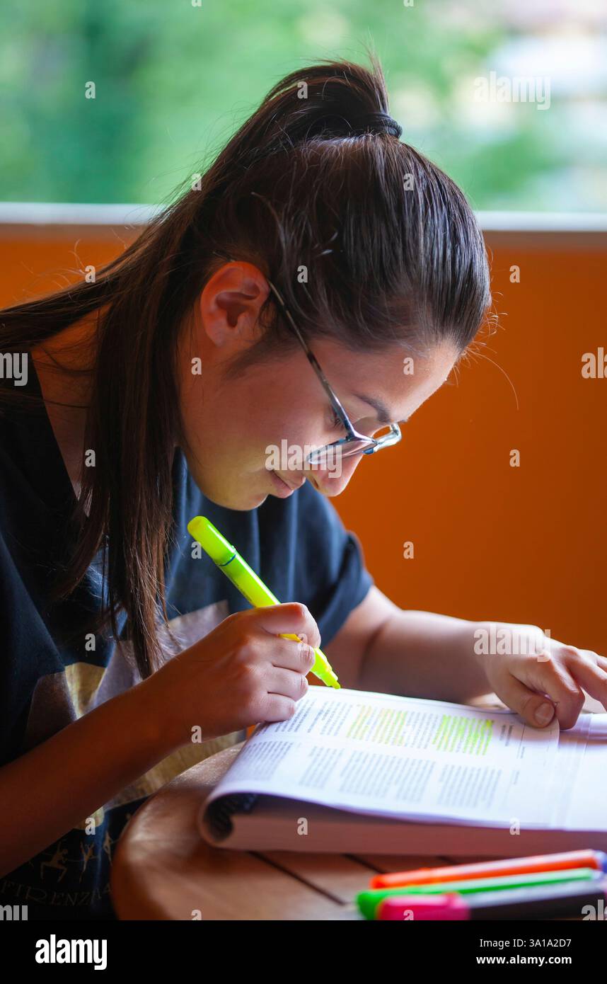 Universitätsstudentin, die für eine Prüfung studiert und Text mit Textmarker unterlegt. Stockfoto