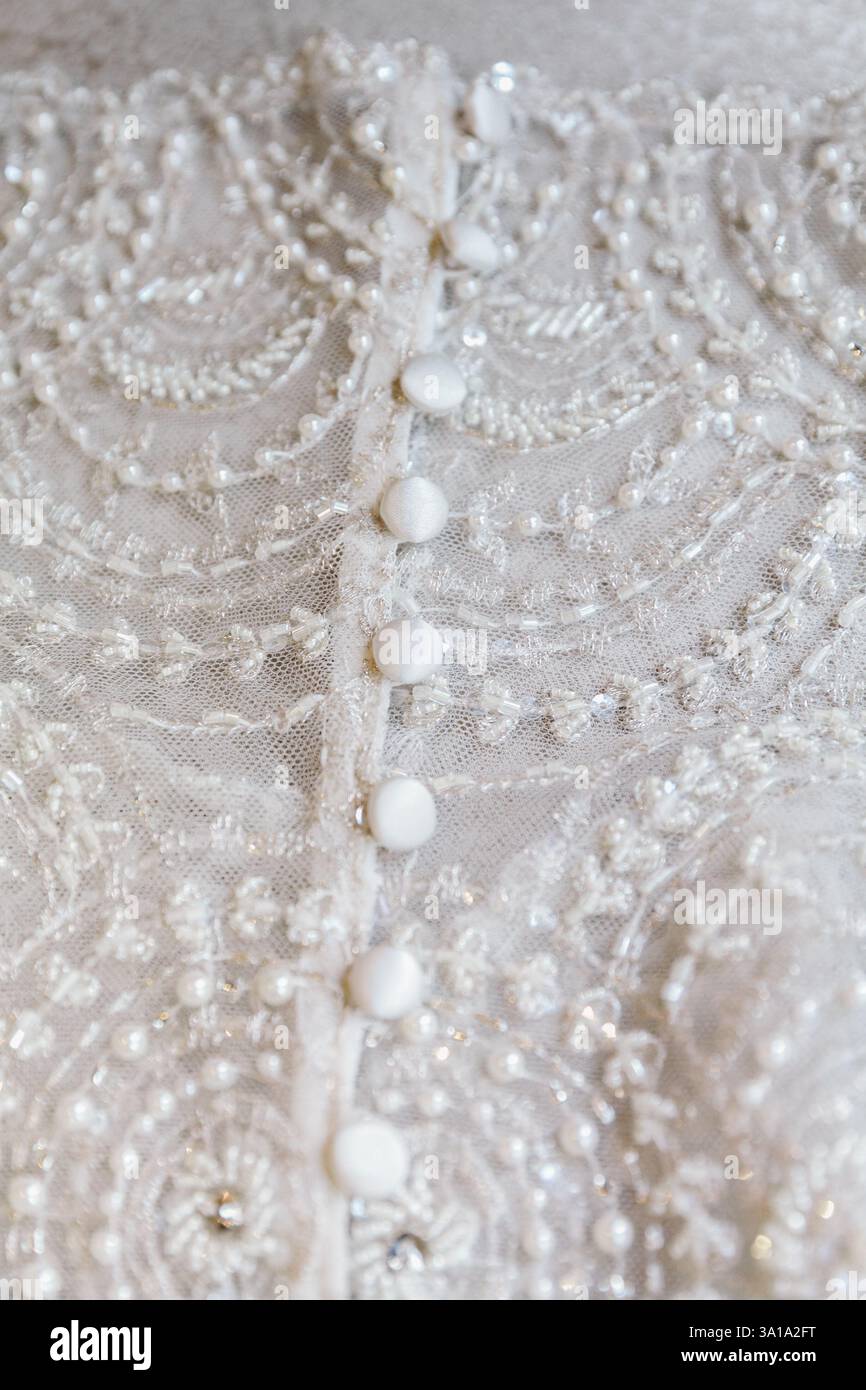 Nahaufnahme aus elegantem Stoff mit filigranen Perlen und Knöpfen, die feine Handwerkskunst zeigen. Stockfoto