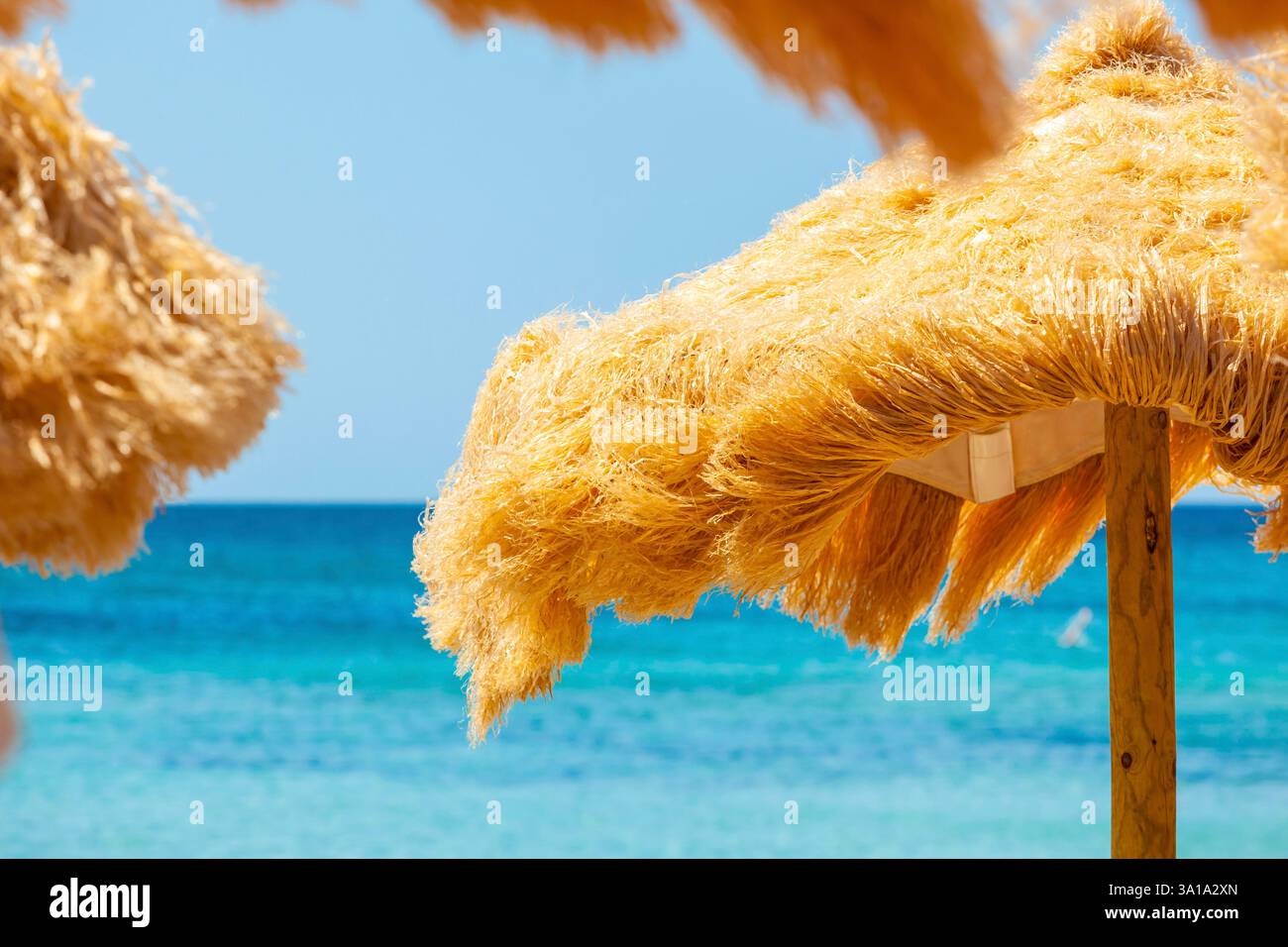 Strand schöne strohgedeckten Sonnenschirmen und leuchtend türkisfarbene Meer, tolle Erholung und Entspannung. Stockfoto