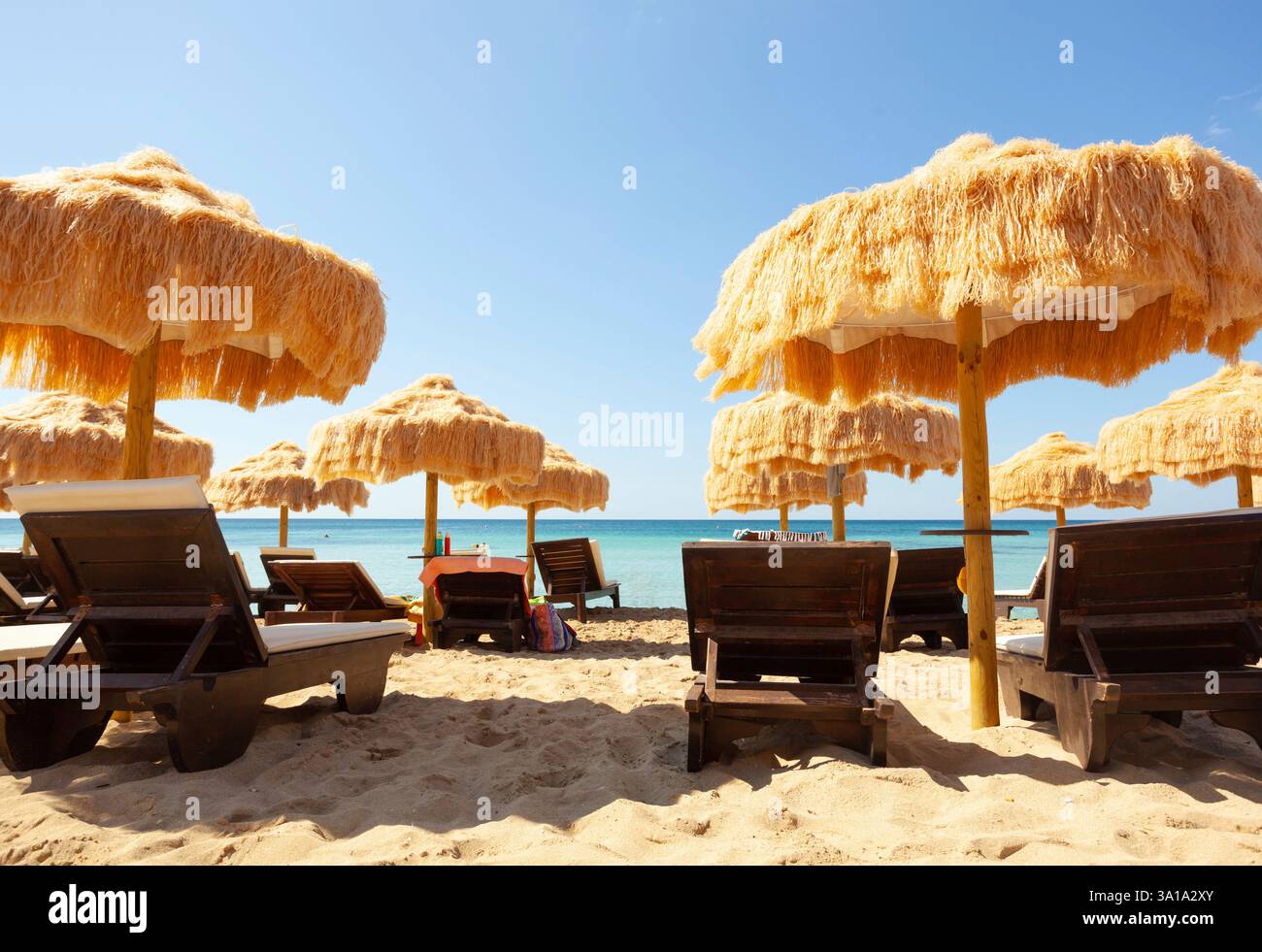 Strand schöne strohgedeckten Sonnenschirmen und leuchtend türkisfarbene Meer, tolle Erholung und Entspannung. Stockfoto