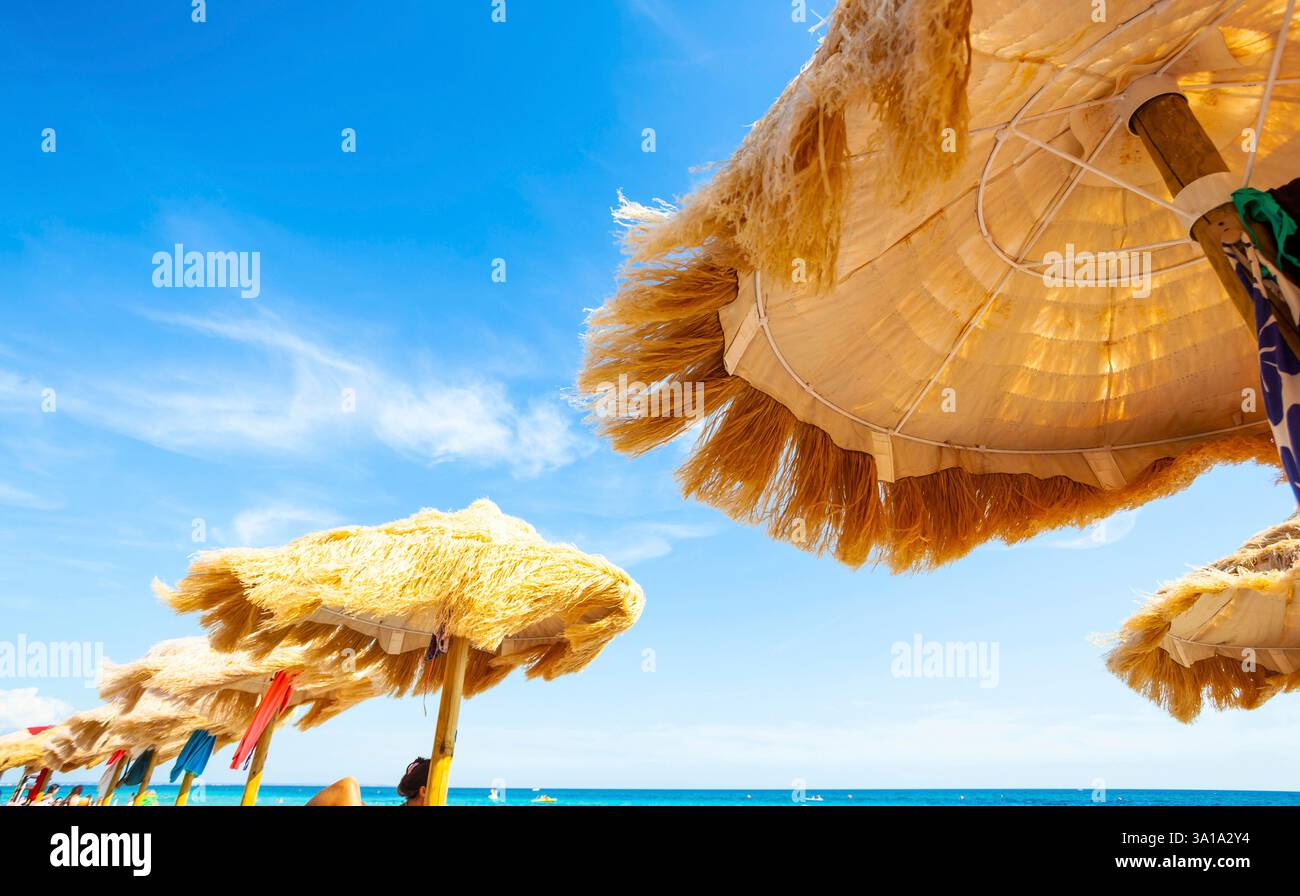 Strand schöne strohgedeckten Sonnenschirmen und leuchtend türkisfarbene Meer, tolle Erholung und Entspannung. Stockfoto