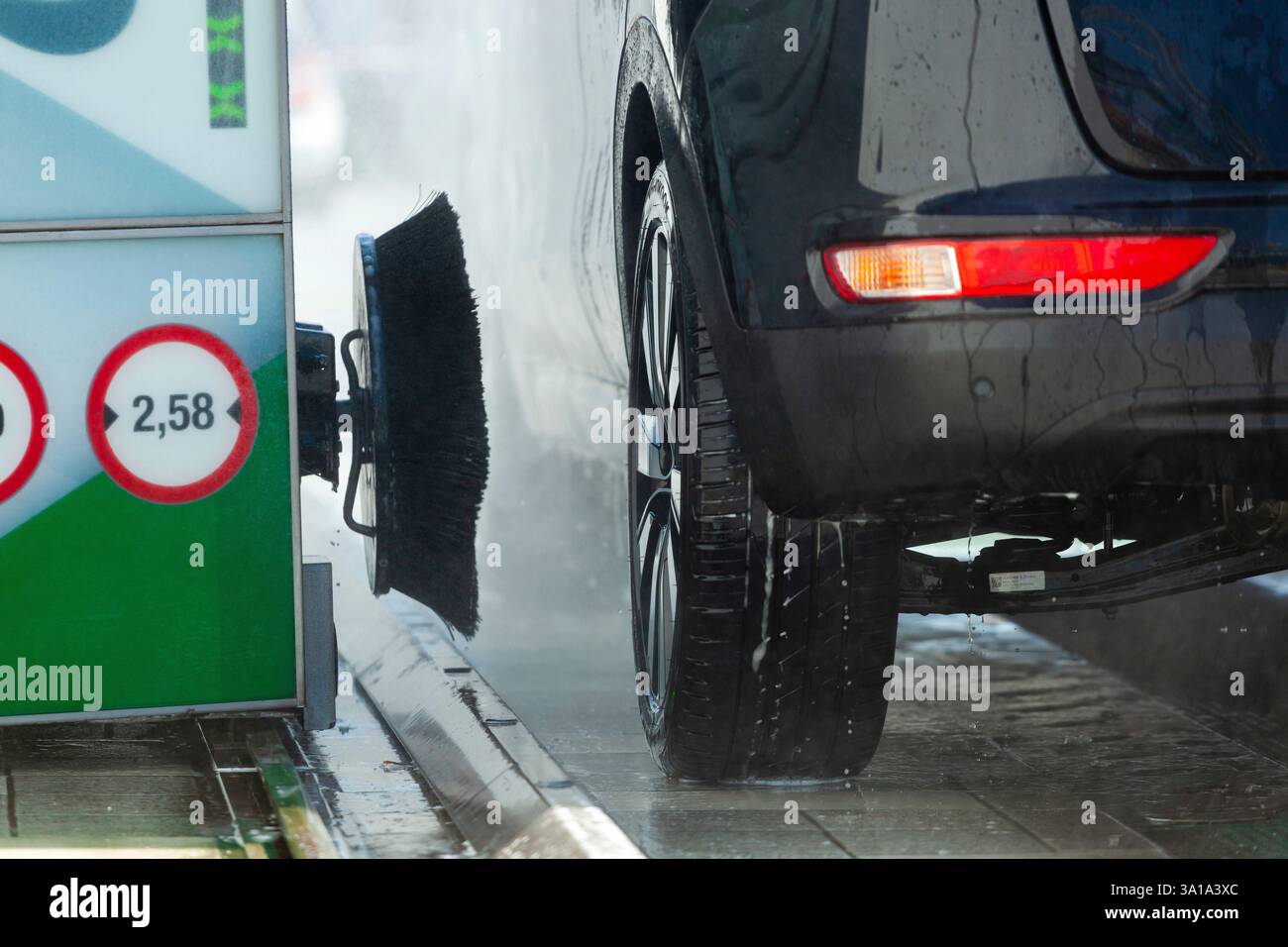 Ein schwarzes Auto wird an einem hellen Wintertag von einer Waschmaschine gewaschen Stockfoto