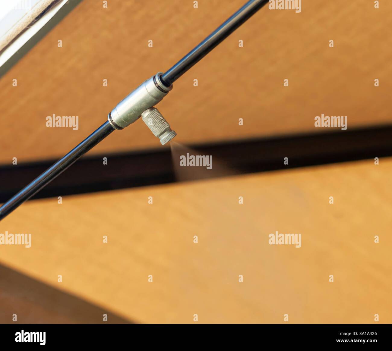 Das Nebelsystem sprüht an heißen Tagen kühl Wasser unter eine Holzdecke, reduziert die Temperatur und kontrolliert das Außenklima, indem Nebel durch Düsen an den Rohren abgegeben wird Stockfoto