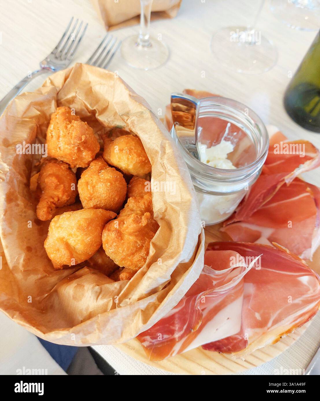 Fangen Sie die köstliche italienische Vorspeisenplatte mit frittierten Teigbällchen, Schinken und Stracchino in einer Nahaufnahme ein Stockfoto