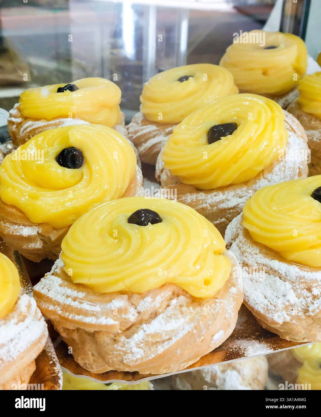 Aus nächster Nähe sehen Sie köstliches Zeppole, klassisches italienisches Gebäck gefüllt mit Vanillepudding und garniert mit einer dunklen Kirsche Stockfoto