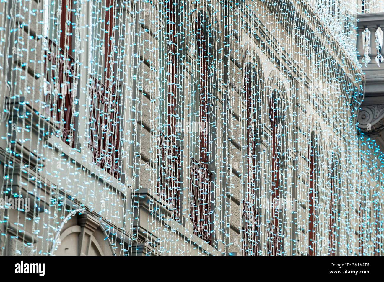 Blaue weihnachtslichter kaskadieren das Äußere eines Gebäudes und erzeugen eine funkelnde Lichterkette Stockfoto