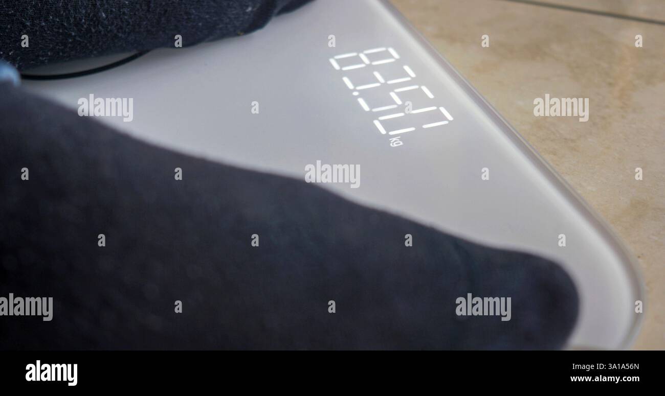 Der Mensch wiegt sich auf digitaler Ebene. Selektiver Fokus auf die elektronische Anzeige. Stockfoto