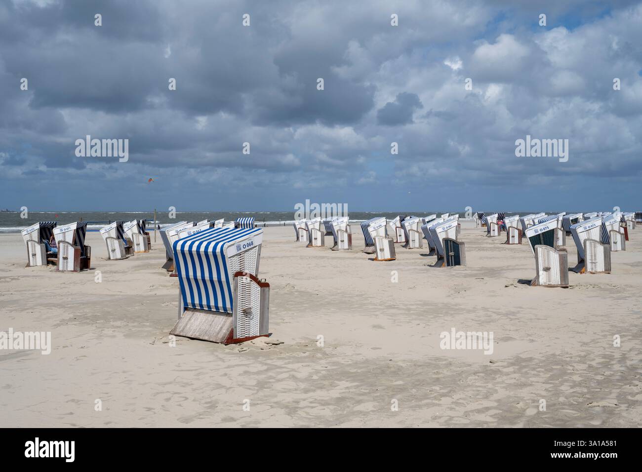 Deutschland, Niedersachsen, Ostfriesland, Norderney, Liegestühle am Sandstrand, dunkle Wolken über der Nordsee Stockfoto