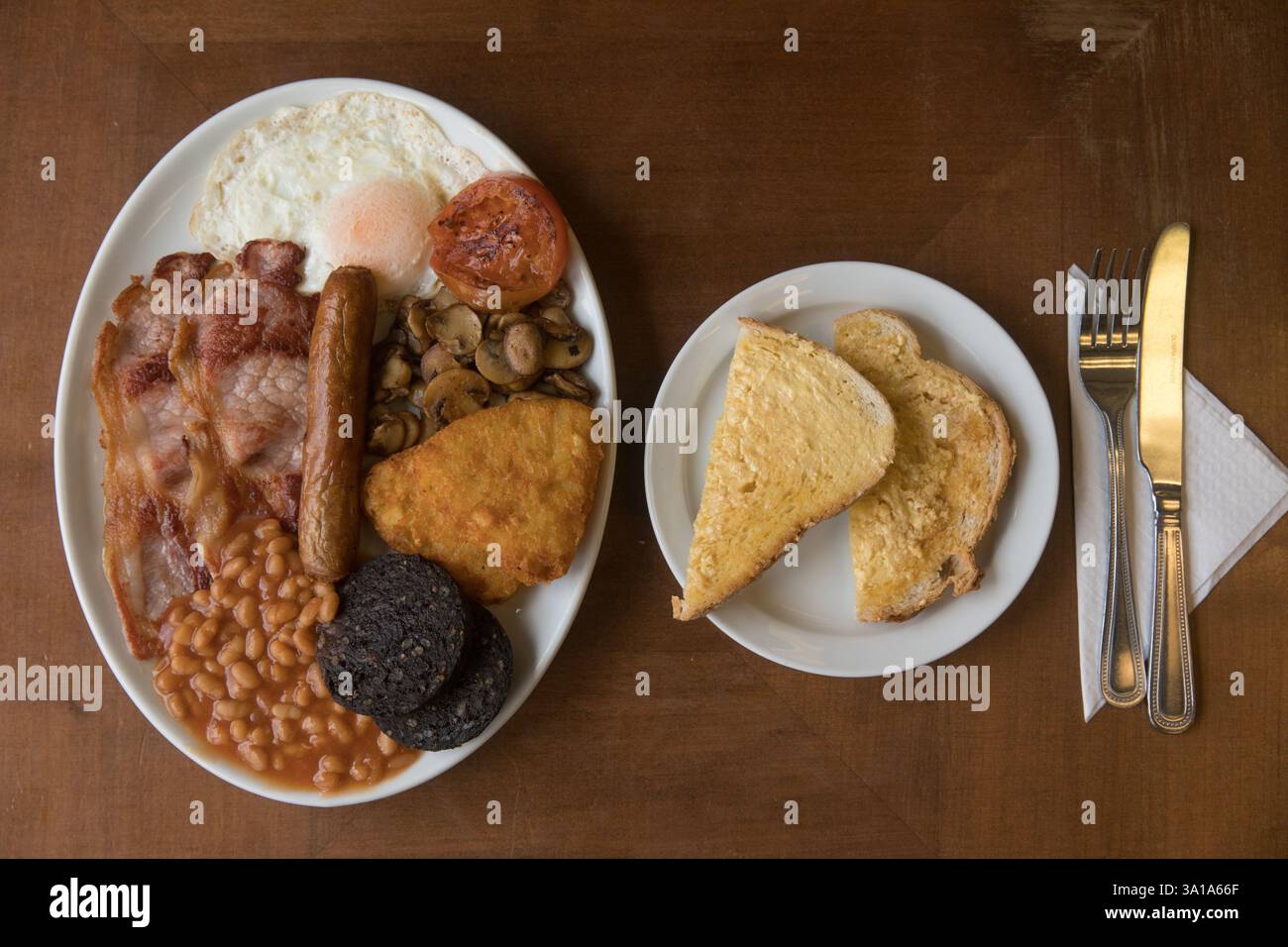 Komplettes irisches Frühstück in einem Café. Buttertoast und Besteck sind ebenfalls vorhanden. Stockfoto