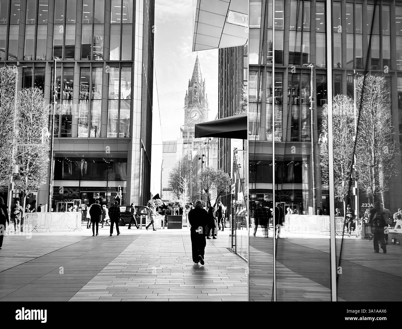 Eine Mischung aus modernen und traditionellen Gebäuden nebeneinander im Stadtzentrum von Manchester, mit dem neogotischen Rathaus-Uhrenturm in der Ferne. Stockfoto