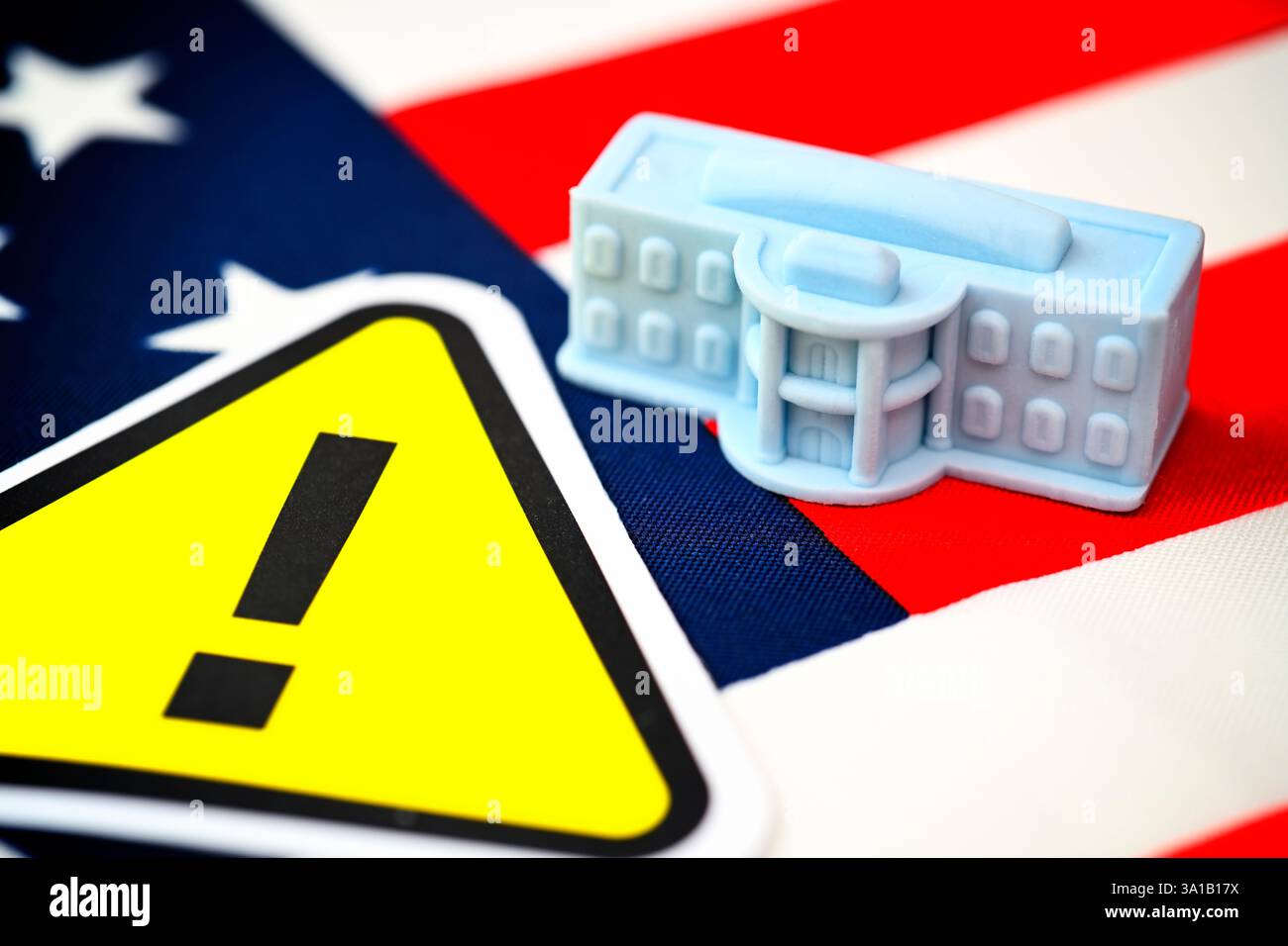 Miniatur des Weißen Hauses auf US-Flagge mit Gefahrenzeichen, symbolisches Foto der US-Regierung Stockfoto