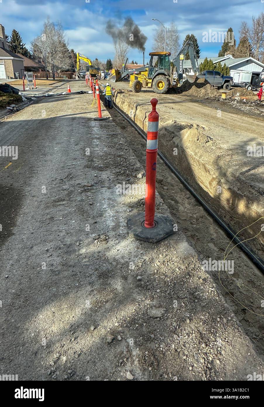 Die Stadt ersetzt alte Wasserleitungen für die Infrastruktur. Große Schwerlastfahrzeuge werden zum Graben, Transportieren und Verlegen neuer Leitungen in der Mitte der Straße verwendet. Stockfoto