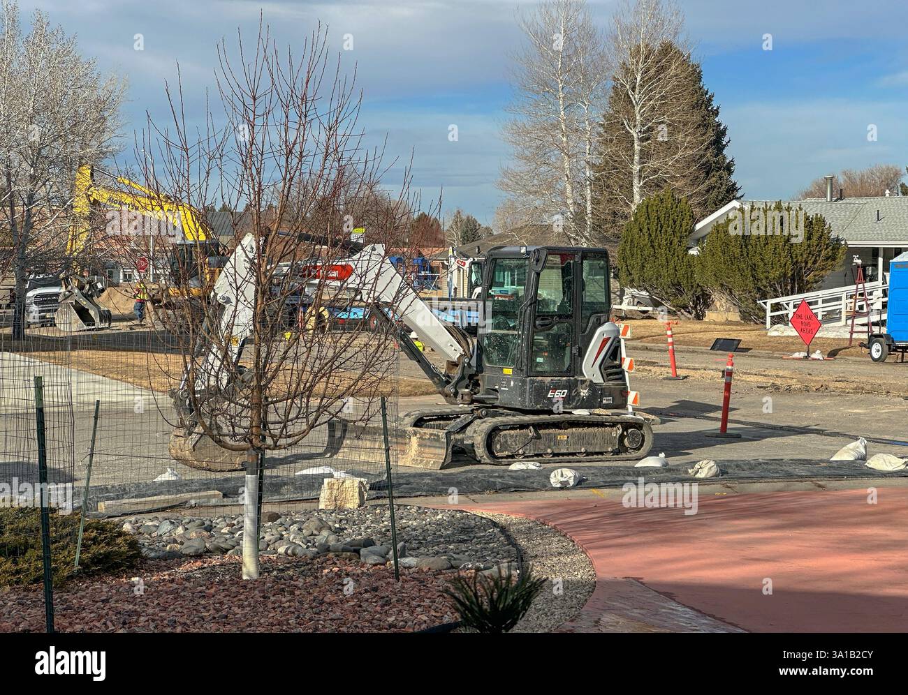 Die Stadt ersetzt alte Wasserleitungen für die Infrastruktur. Große Schwerlastfahrzeuge werden zum Graben, Transportieren und Verlegen neuer Leitungen in der Mitte der Straße verwendet. Stockfoto