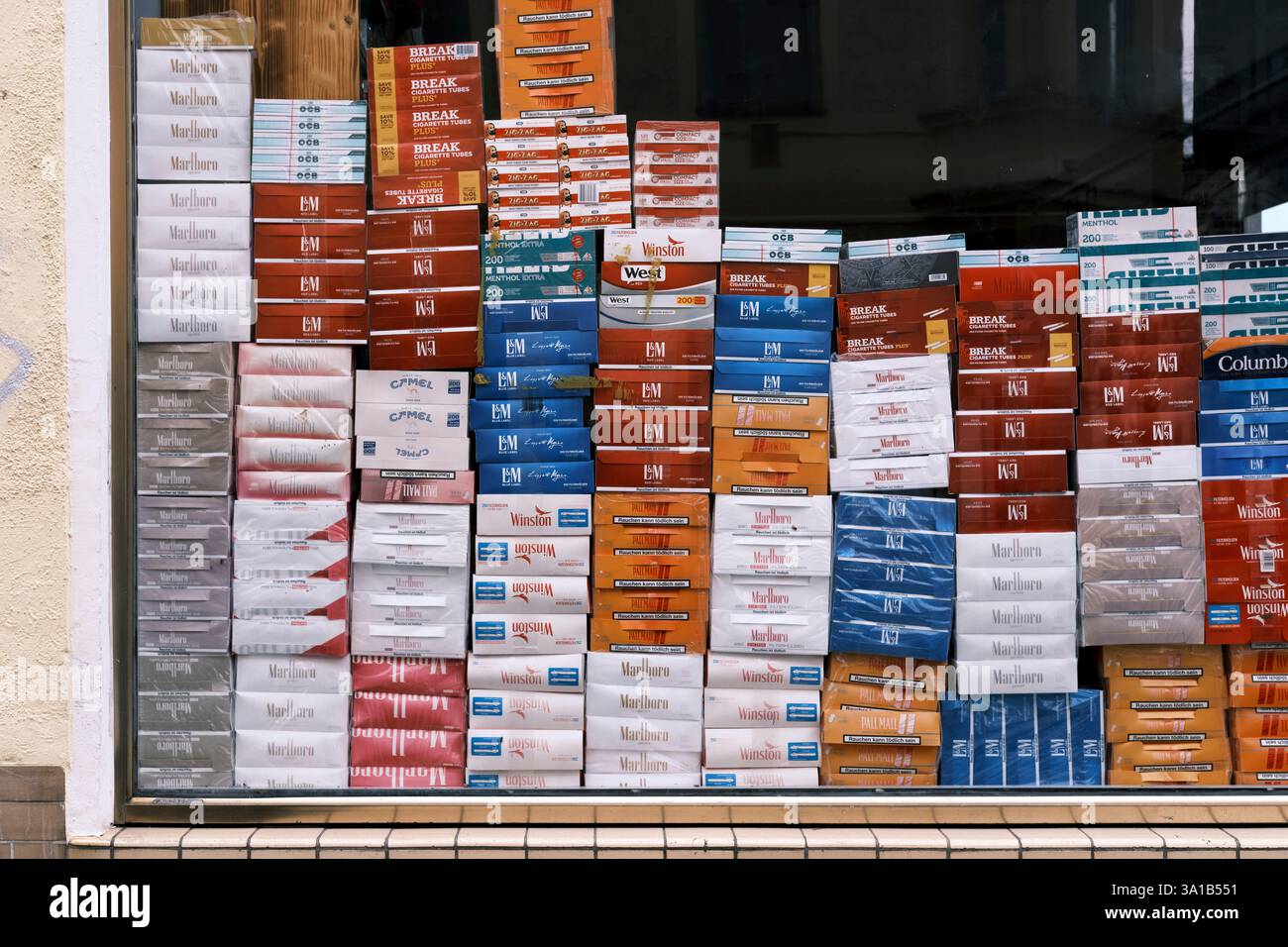 Zigarettenpackungen verschiedener Marken werden im Schaufenster eines Kiosks gestapelt. Fast das gesamte Fenster ist bedeckt. Stockfoto