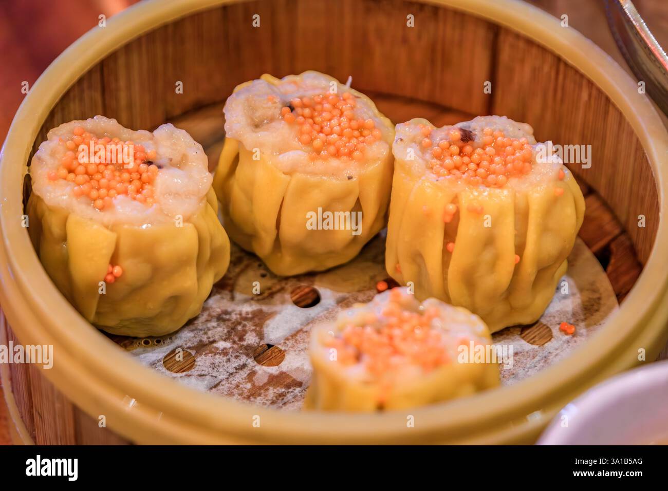 Goldene Garnelen und Schweinefleisch Shu Mai Dim Sum Knödel in einem San Francisco Restaurant mit chinesischer Küche, garniert mit Krabbenrogen, gedämpft in einem Bambuskorb Stockfoto