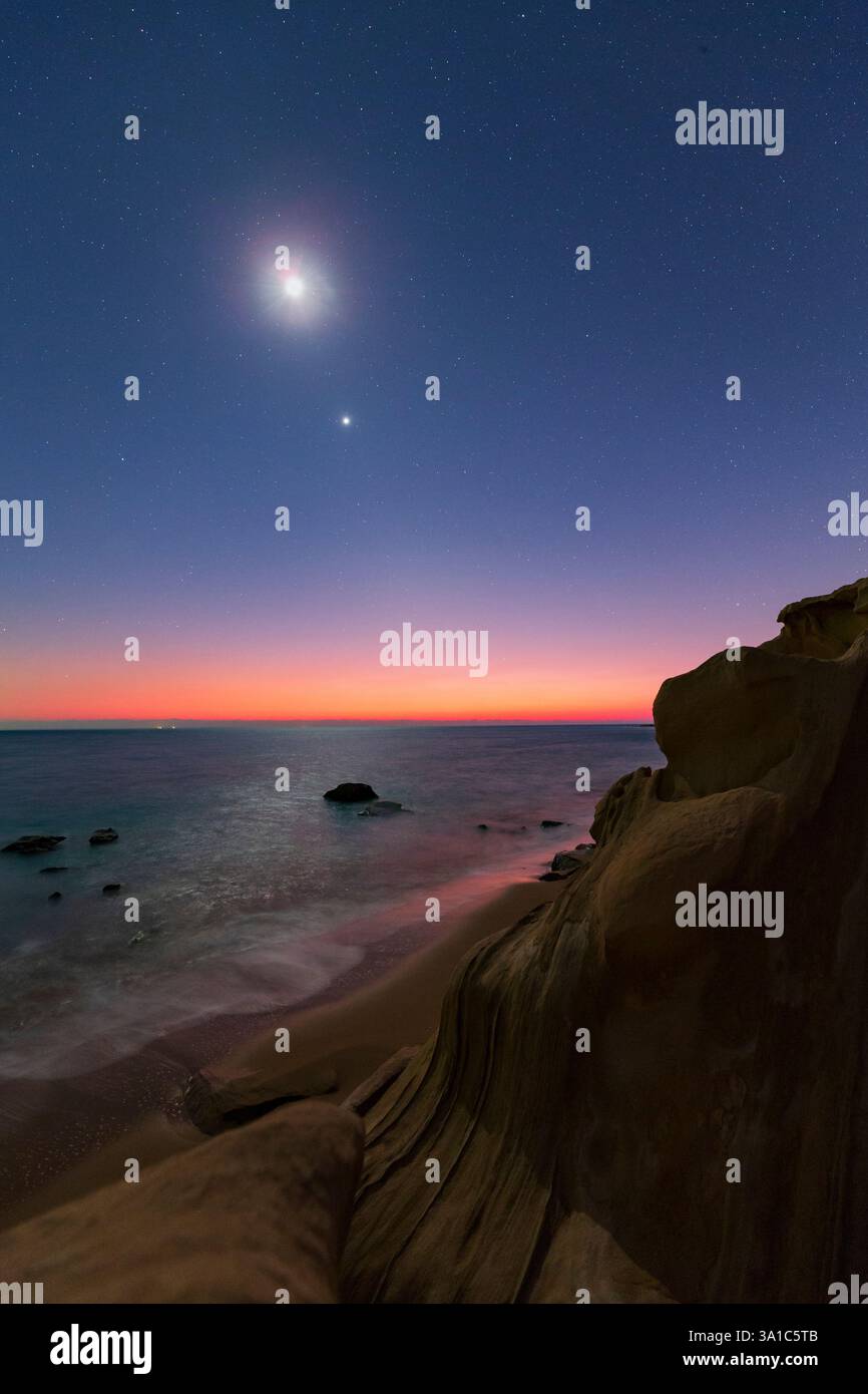 Mond, Venus und Saturn bei Sonnenuntergang, gesehen von einem felsigen Ufer im Persischen Golf im südlichen Iran. Stockfoto
