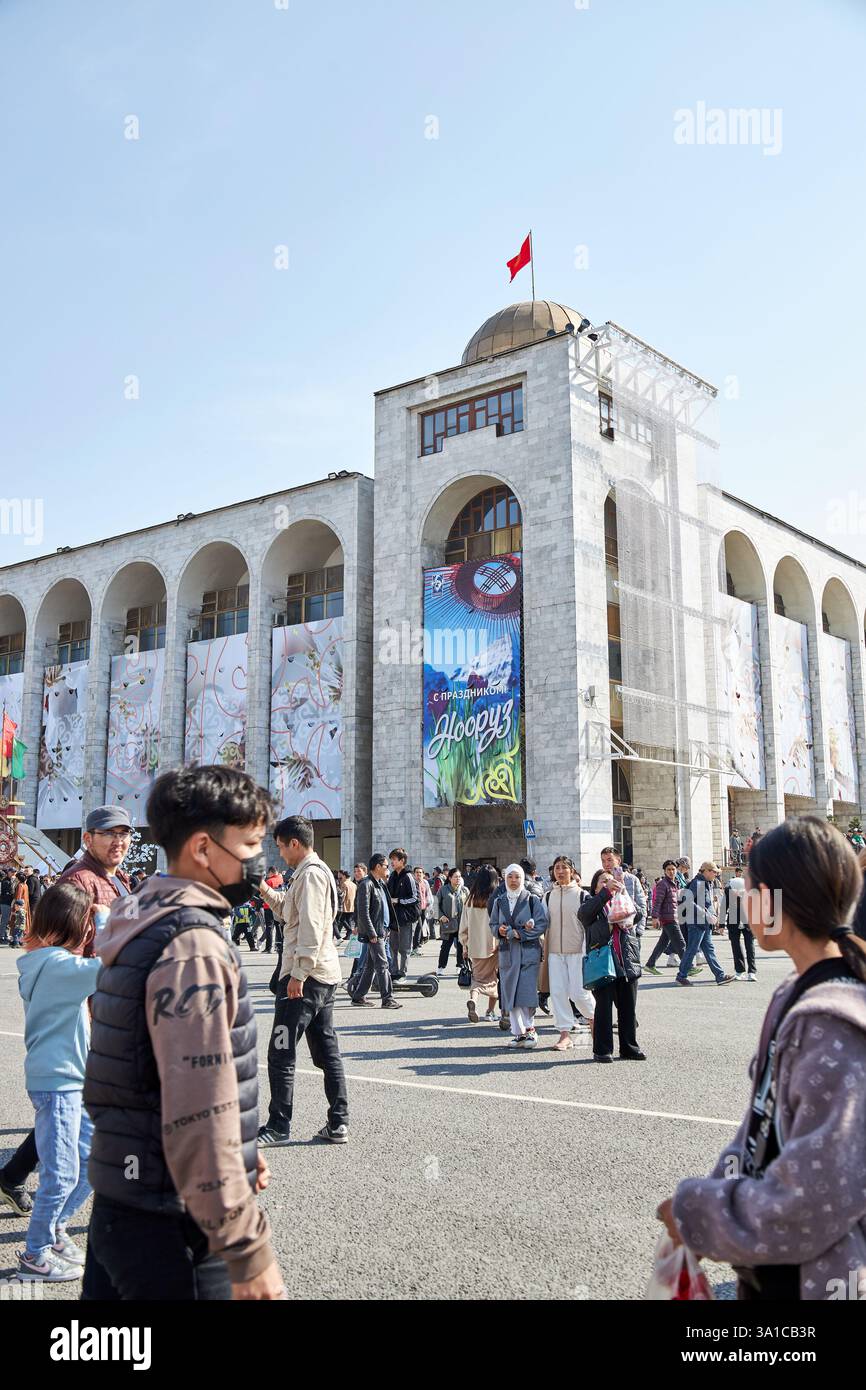 Nowruz-Feier, Leute spazieren gehen, Ala-Too Stadtplatz. Inschrift auf dem Banner: Nooruz Happy Holidays. Feiertage feiern. Bischkek, Kirgisistan - 21 Stockfoto
