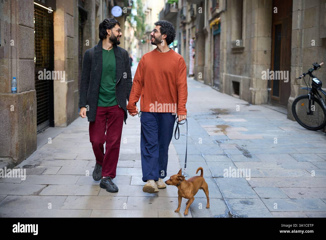 Schwule Paare, die Hände halten und mit Hund in barcelona laufen Stockfoto
